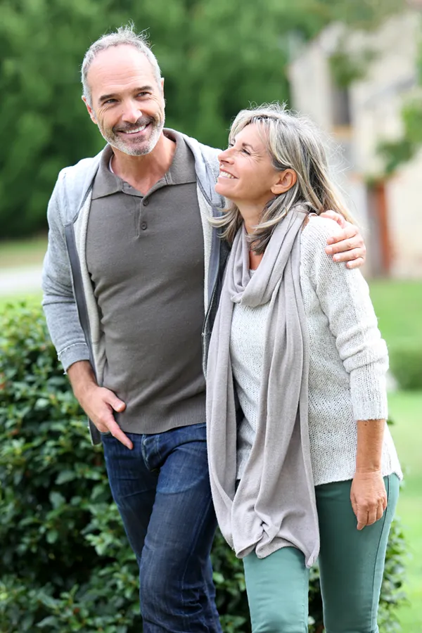 A mature couple in gray toned clothes and jeans walk happily outside, happy with their successful bioidentical hormone treatments from Shelley Cole, M.D. of Healthy Success in Temple, Texas.