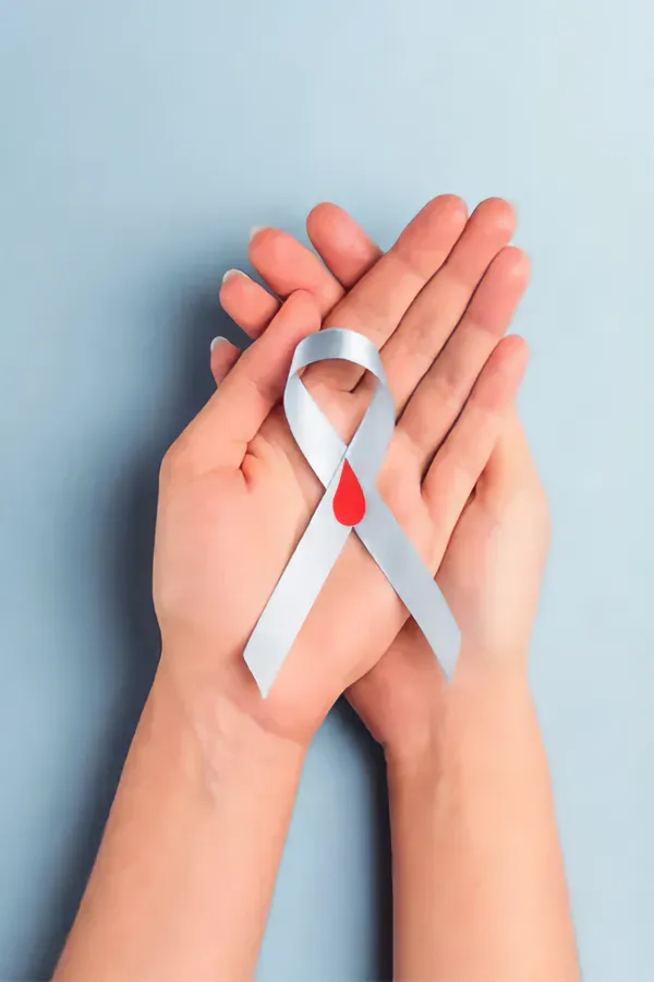 A woman's hands holding a white ribbon with a red drop symbol on it, symbolizing diabetes treatment from Shelley Cole, M.D. of Healthy Success in Temple, Texas.