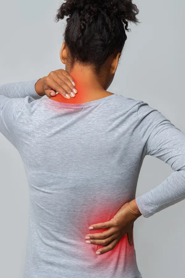 An image from behind of a woman suffering from Fibromyalgia holding her hands on her neck and lower back. Get fibromyalgia treatment from Shelley Cole, M.D. of Healthy Success in Temple, Texas.