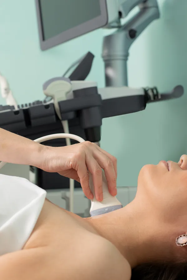A woman gets a thyroid scan from a doctor in a clinic. Get help with Hashimoto's Thyroiditis from Shelley Cole, M.D. of Healthy Success in Temple, Texas.