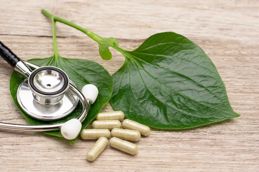 A stethoscope, leaves, and medicine capsules on a wood table, representing Integrative Medicine provided by Shelley Cole, M.D. of Healthy Success in Temple, Texas.