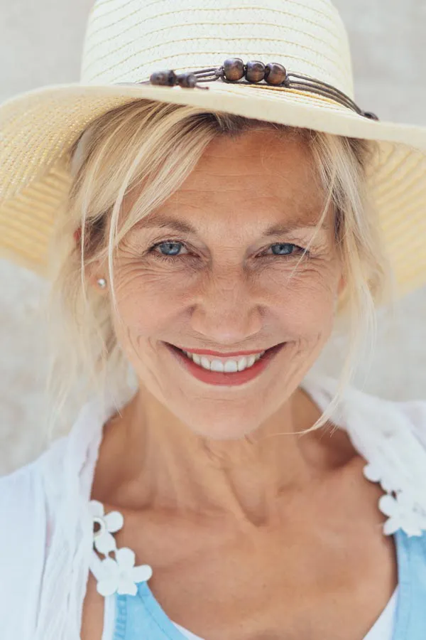 A beautiful, smiling older woman with blonde hair and a sunhat, happy with menopause treatment from Shelley Cole, M.D. of Healthy Success in Temple, Texas.