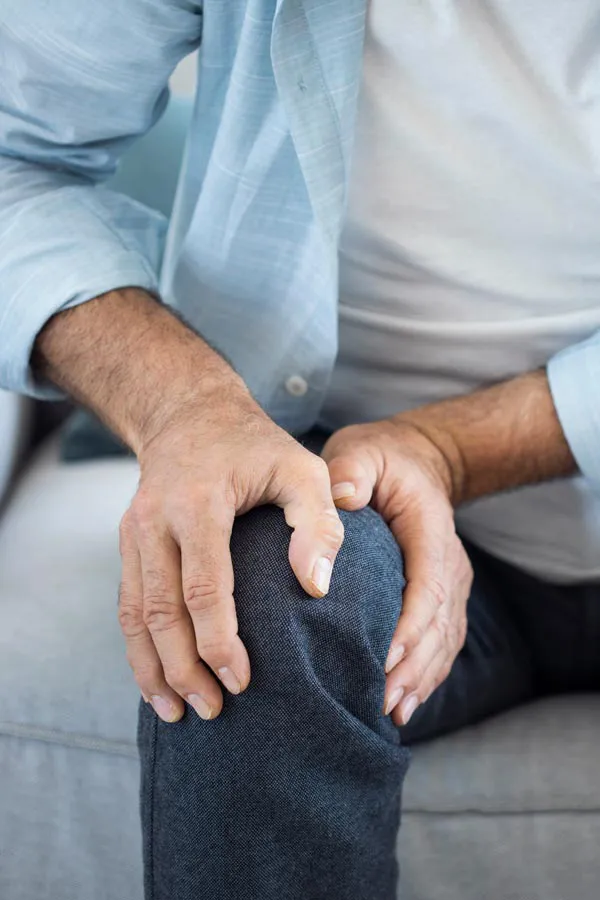 A close-up of a man holding his knee while experiencing pain from osteoporosis. Get osteoporosis treatment from Shelley Cole, M.D. of Healthy Success in Temple, Texas.