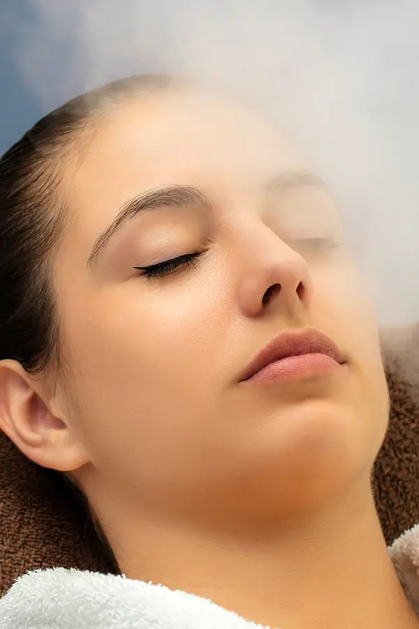 Close-up of a woman with her eyes closed breathing in mist. Get ozone therapy from Shelley Cole, M.D. of Healthy Success in Temple, Texas.
