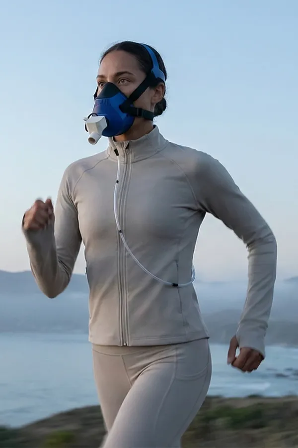 A woman with a PNOE breath analysis device on a run on the beach. Get PNOE metabolic analysis testing from Shelley Cole, M.D. of Healthy Success in Temple, Texas.