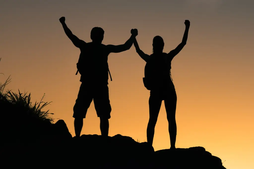 A couple raises they're arms in triumph at the summit of a sunset hike. Schedule prolozone treatment from Shelley Cole, M.D. of Healthy Success in Temple, Texas.