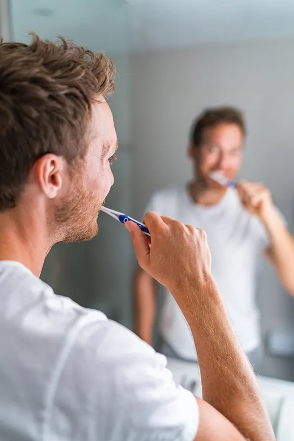 A happy man brushing his teeth. Get Tooth Remineralization treatment from Shelley Cole, M.D. of Healthy Success in Temple, Texas.